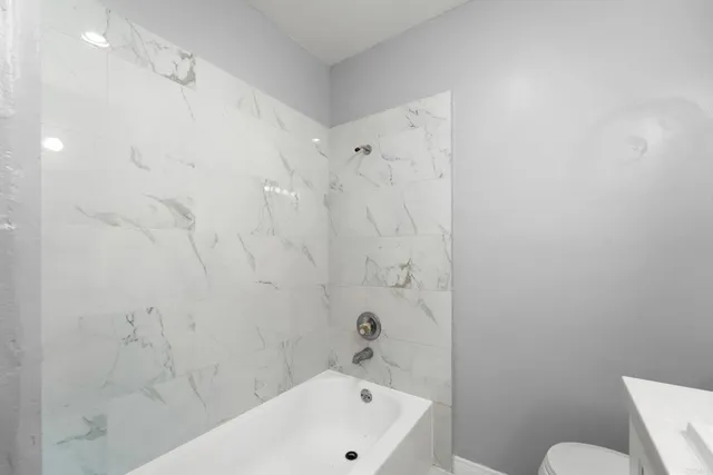 a bathroom with a white bath tub a toilet and a sink