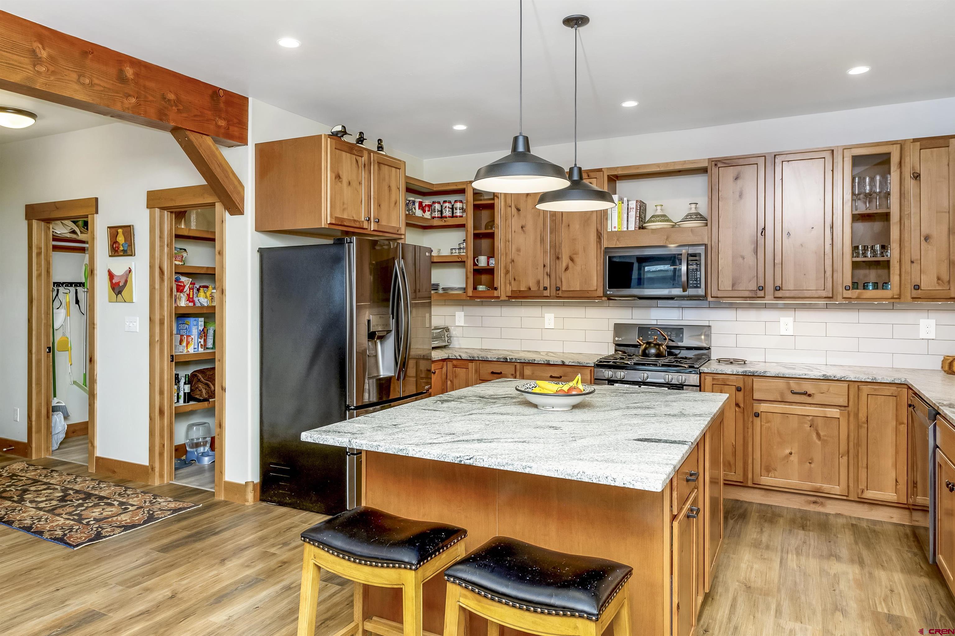48 Elk Valley Road, Unit B Crested Butte, CO 81224 - Photo 9 of 34 a kitchen with stainless steel appliances granite countertop a stove a refrigerator a kitchen island a sink and a wooden cabinets