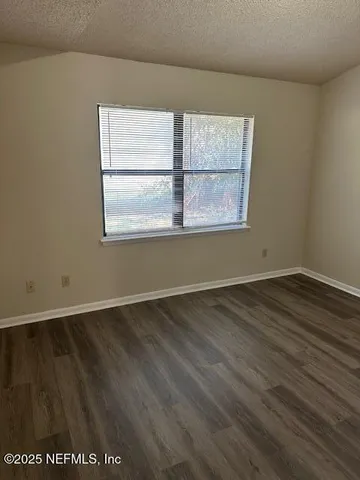 an empty room with wooden floor and window