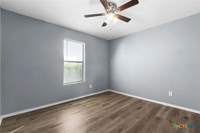 an empty room with a window and a fan
