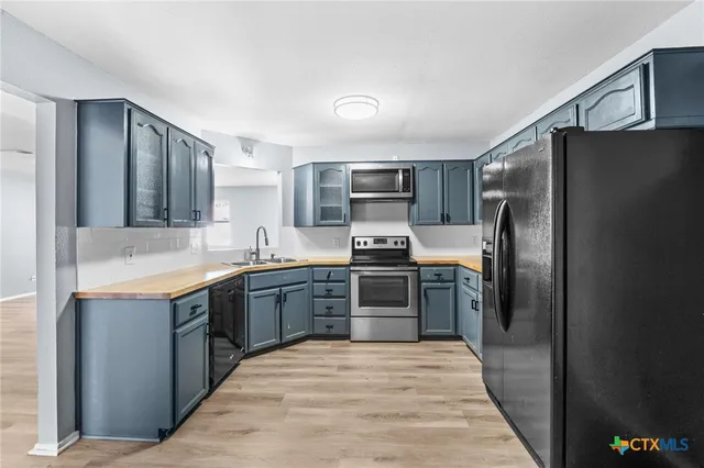 a large kitchen with stainless steel appliances granite countertop a refrigerator and a sink