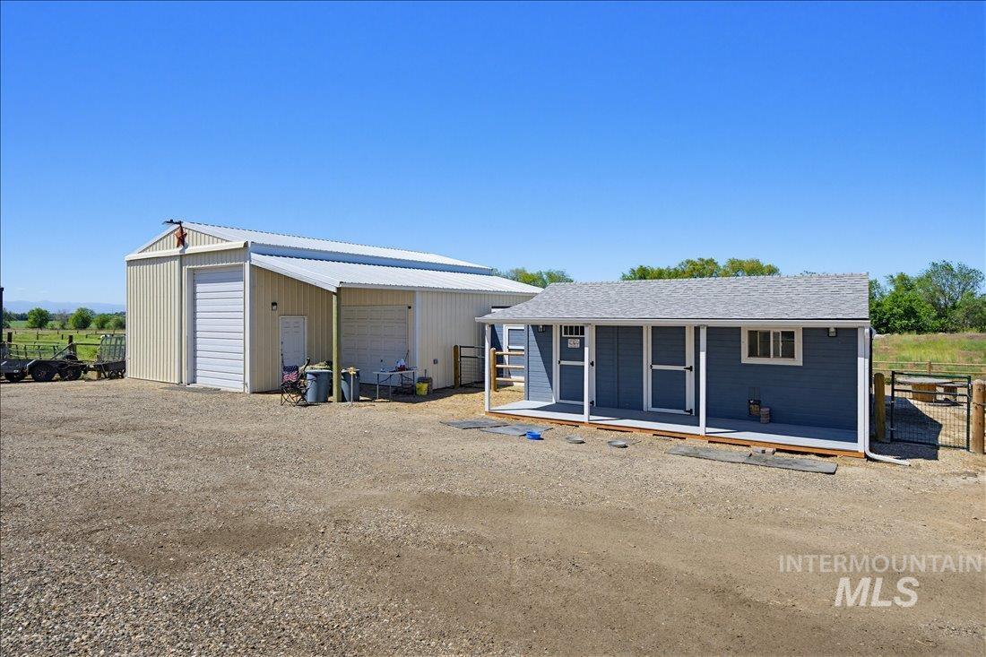 24623 Falcon Lane Caldwell, ID 83607 - Photo 37 of 40 Two structures featuring a large metal-sided building with a roll-up door and a smaller blue-sided building with a covered porch and white trim