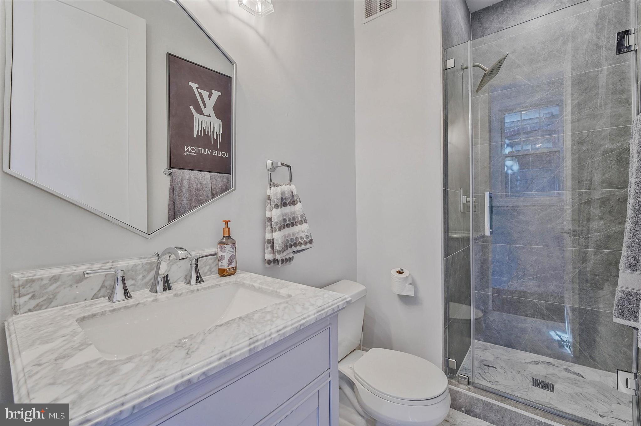 1240 Columbia Road Northwest, Unit 1 Washington, DC 20009 - Photo 6 of 25 a bathroom with a granite countertop sink a mirror and a toilet