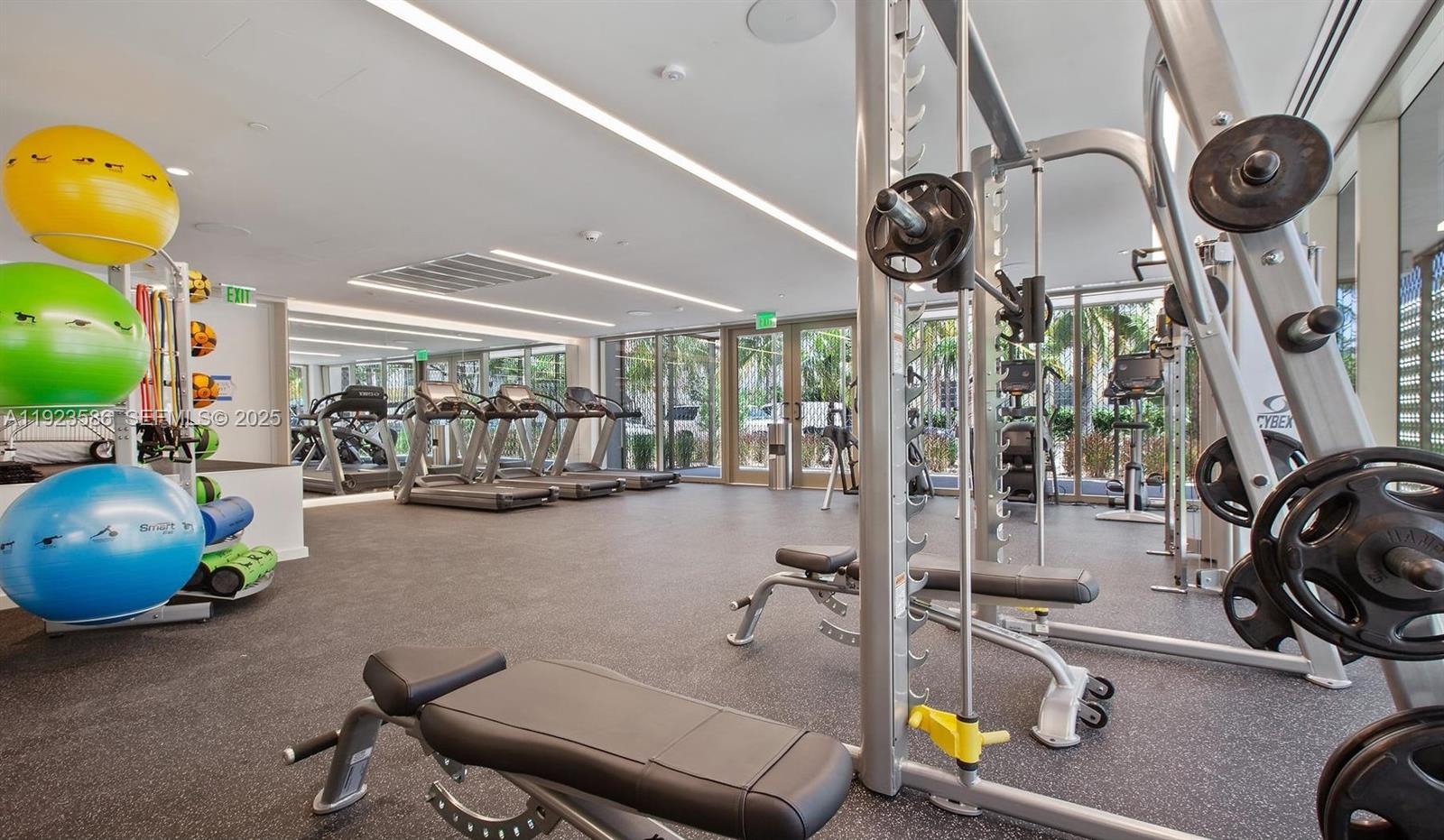 300 Collins Avenue, Unit PH2 Miami Beach, FL 33139 - Photo 19 of 21 a room with gym equipment and a chandelier