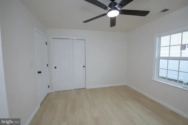 an empty room with a window and a fan