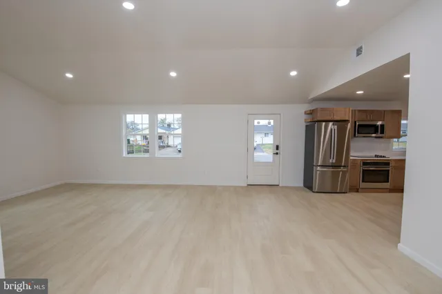 an empty room with stainless steel appliances kitchen island granite countertop a stove a sink a refrigerator and cabinets