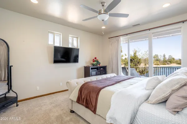 a bedroom with a large bed and a flat tv screen on dresser