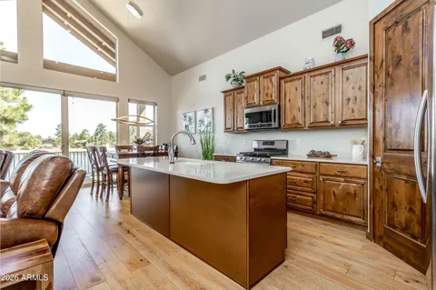 a kitchen with stainless steel appliances granite countertop a stove top oven a sink a dining table and chairs
