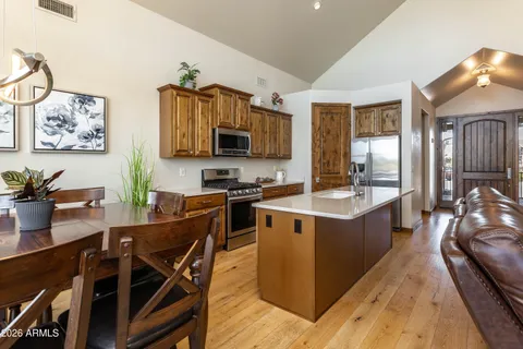 a kitchen with stainless steel appliances granite countertop a stove top oven a sink a dining table and chairs with wooden floor