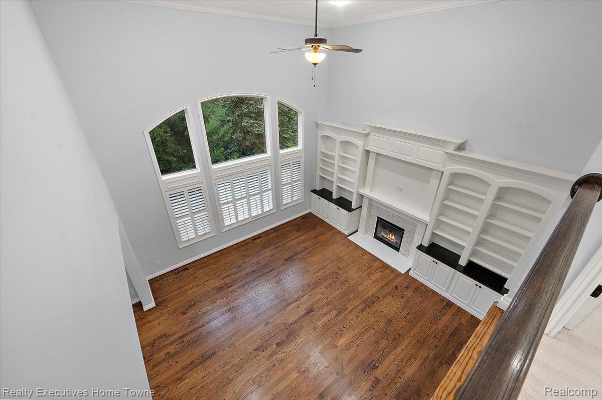 2919 North Addison Circle Rochester, MI 48306 - Photo 30 of 69 Two-story living area featuring wood-finish flooring, a ceiling fan, and large arched windows with plantation shutters