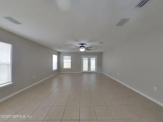 an empty room with windows and ceiling fan