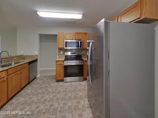 a kitchen with stainless steel appliances granite countertop a refrigerator and a sink