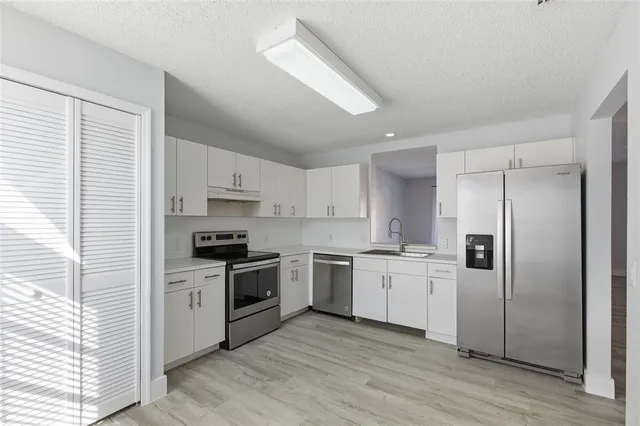 a kitchen with granite countertop white cabinets and white appliances
