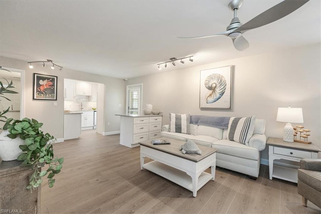 626 12th Avenue South, Unit 626 Naples, FL 34102 - Photo 14 of 50 a spacious bedroom with a bed a couch and paintings on the wall