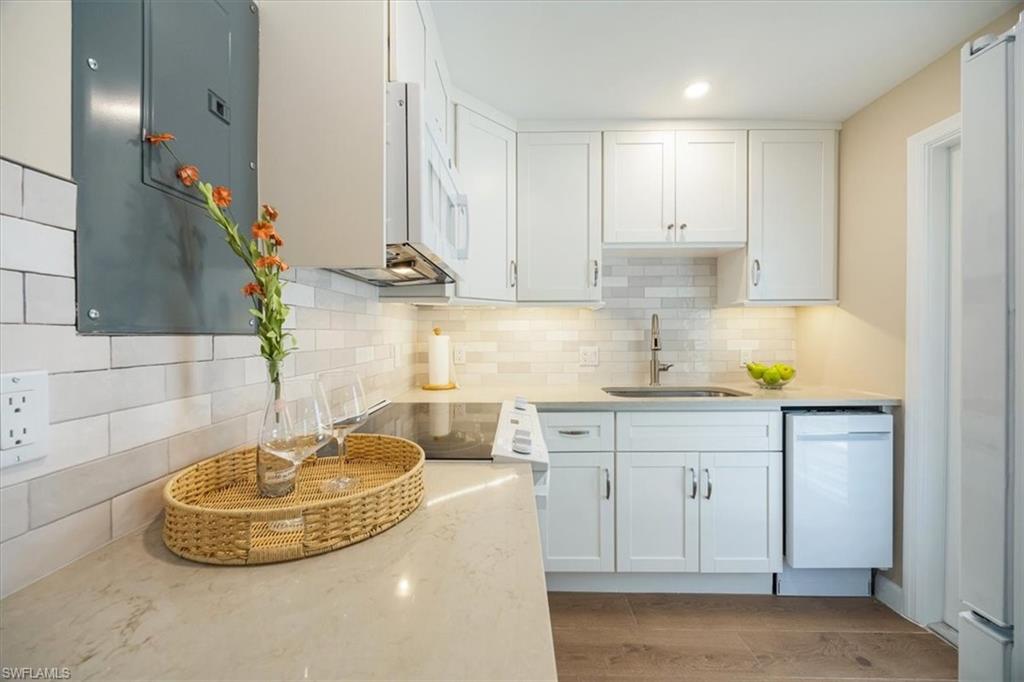 626 12th Avenue South, Unit 626 Naples, FL 34102 - Photo 18 of 50 a kitchen with a sink and a stove with white cabinets