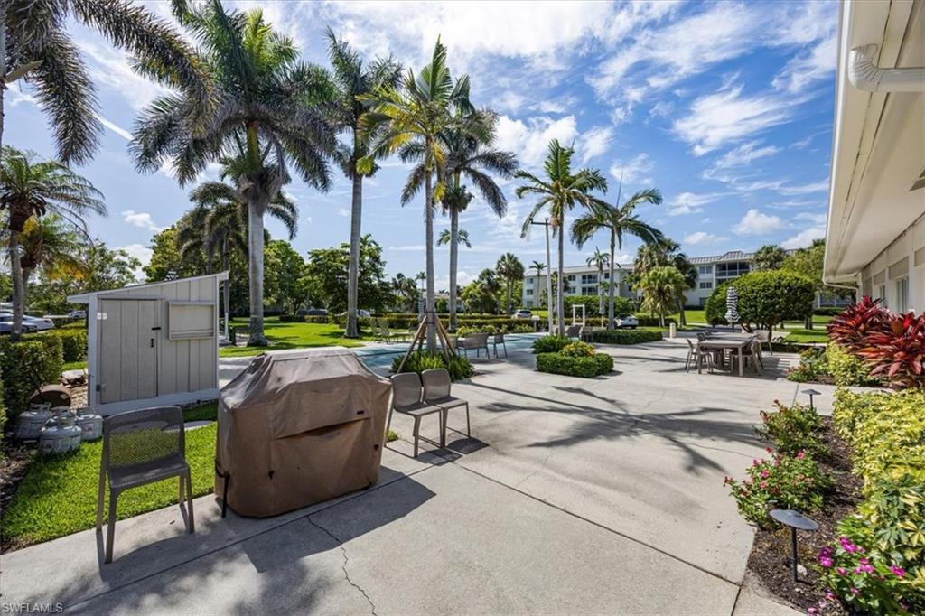 626 12th Avenue South, Unit 626 Naples, FL 34102 - Photo 48 of 50 a view of a patio with dining table and chairs under an umbrella