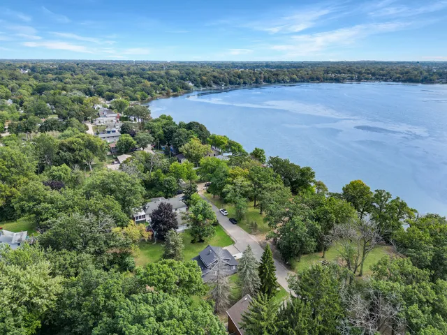 an aerial view of a houses with outdoor space and trees all around