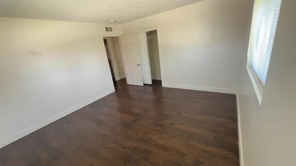 a view of an empty room with wooden floor and a window