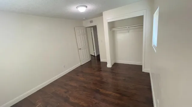 a view of an empty room with wooden floor and closet