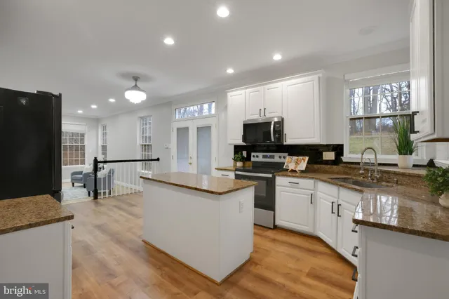 a kitchen with stainless steel appliances kitchen island granite countertop a refrigerator and a stove top oven