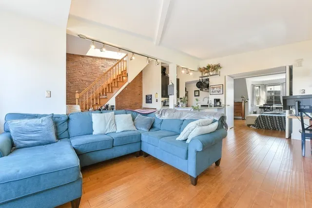 a living room with furniture kitchen view and a large window