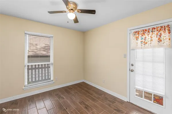 a view of an empty room with a window and wooden floor
