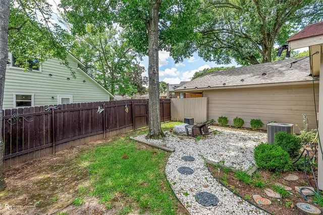 a view of backyard with wooden fence and a large tree