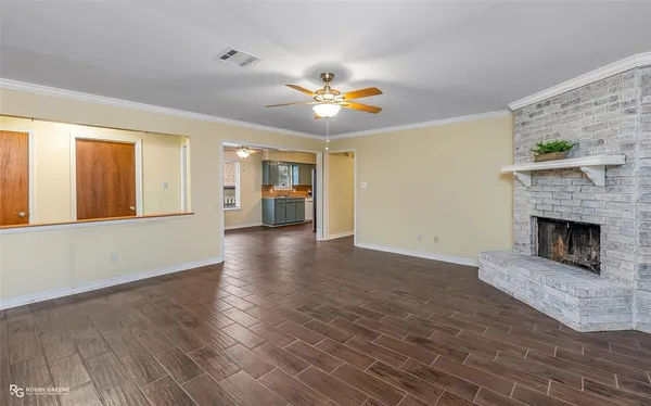 a view of a livingroom with a fireplace a ceiling fan and windows