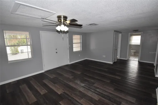 a view of an empty room with wooden floor and a window