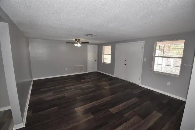 a view of an empty room with wooden floor and a window
