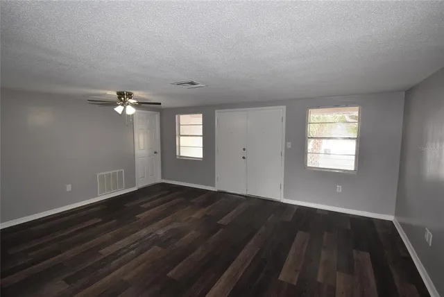a view of empty room with wooden floor and fan