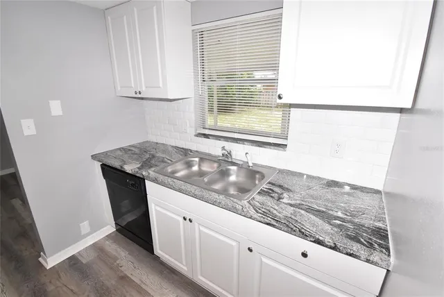 a kitchen with granite countertop white cabinets and a sink