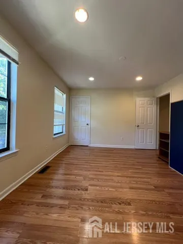a view of an empty room with window and wooden floor