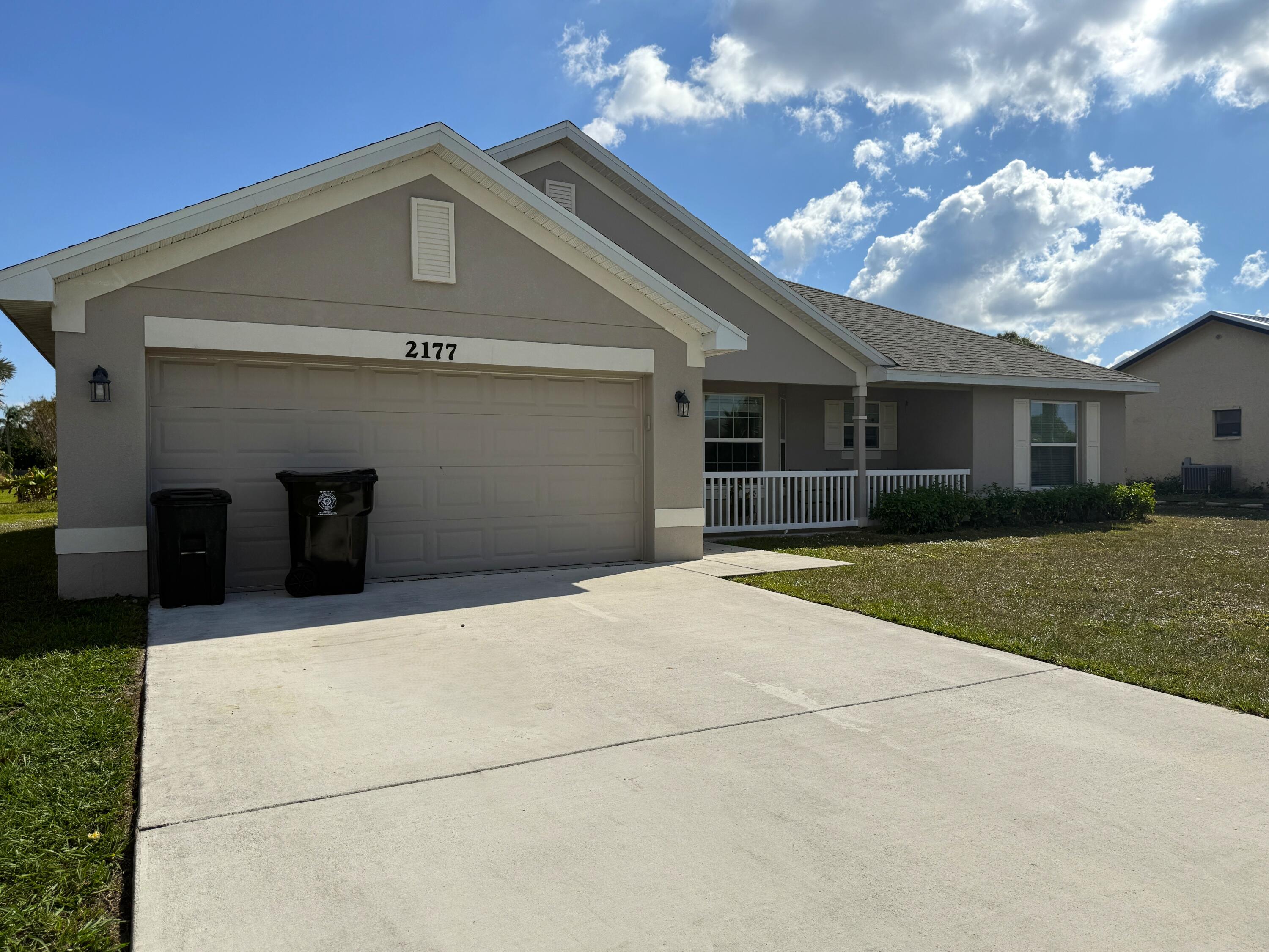 2177 Southeast Dolphin Road Port St. Lucie, FL 34952 - Photo 12 of 13 a front view of a house with a yard and garage
