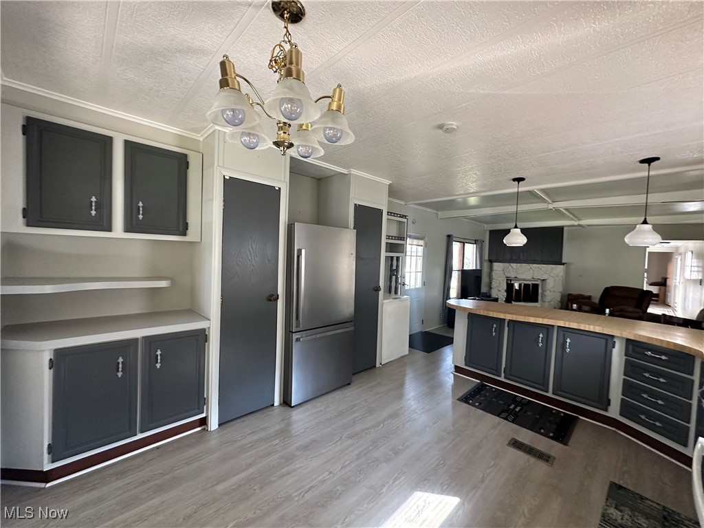 5852 Cleveland Road, Unit 21 Wooster, OH 44691 - Photo 9 of 17 Kitchen featuring a fireplace, a textured ceiling, hardwood / wood-style floors, and stainless steel refrigerator