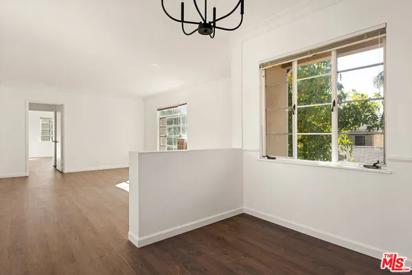 a view of an empty room with wooden floor and window