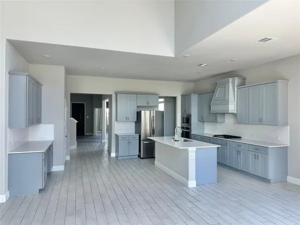 a kitchen with stainless steel appliances a stove top oven a sink dishwasher and a refrigerator