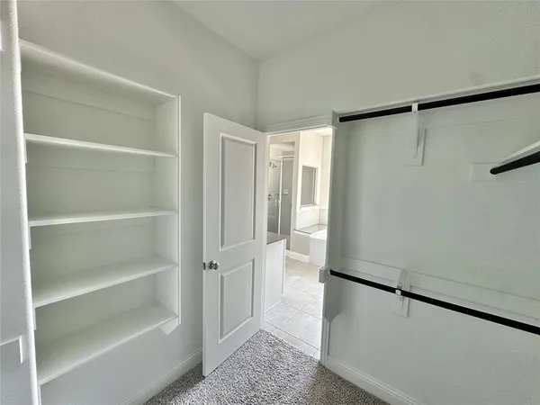 a view of walk in closet with empty racks