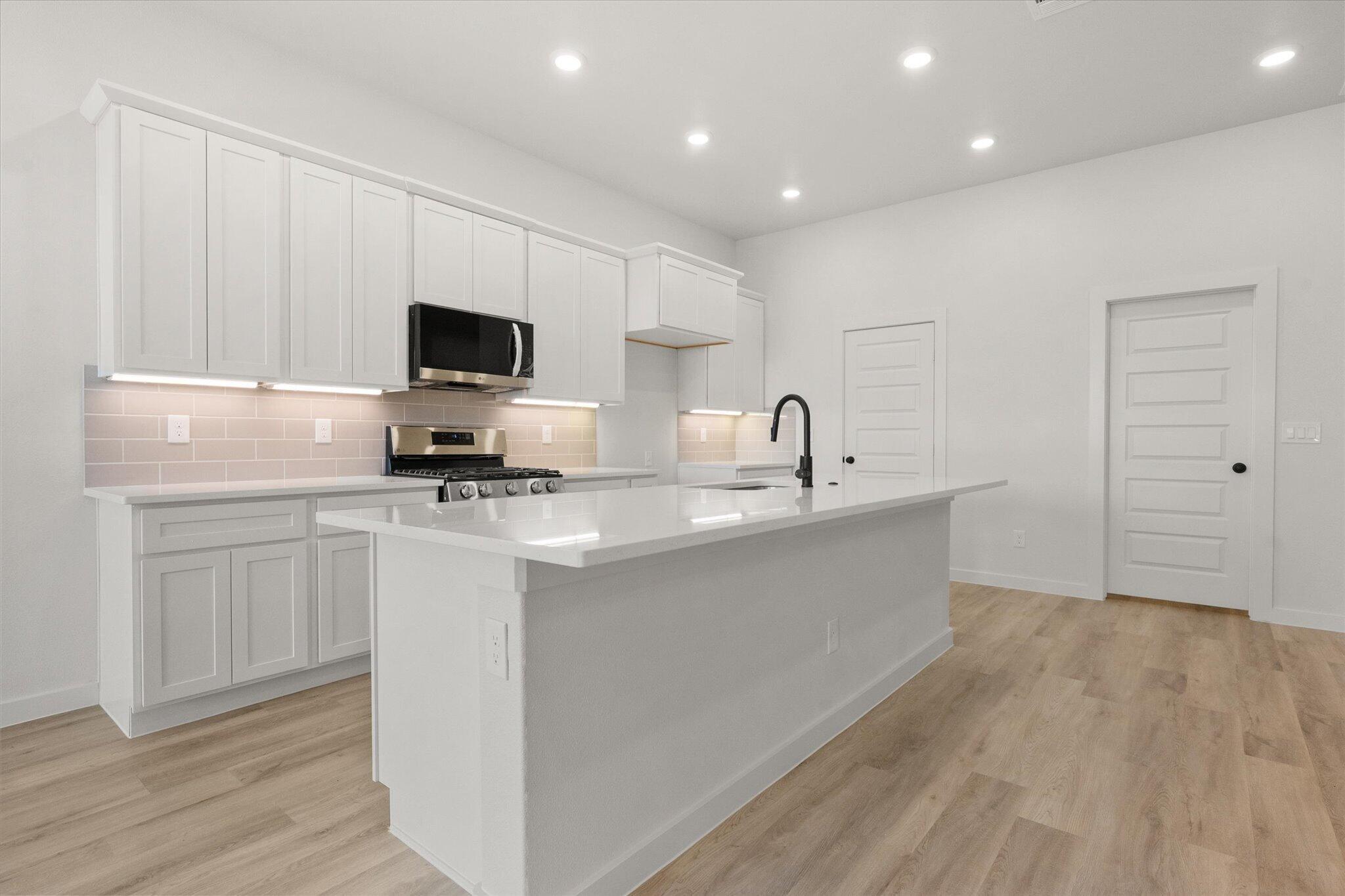 1203 East 30th Street Wolfforth, TX 79382 - Photo 9 of 25 a kitchen with a sink a microwave and cabinets