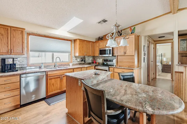 a kitchen with stainless steel appliances granite countertop a sink a stove a refrigerator cabinets and a dining table