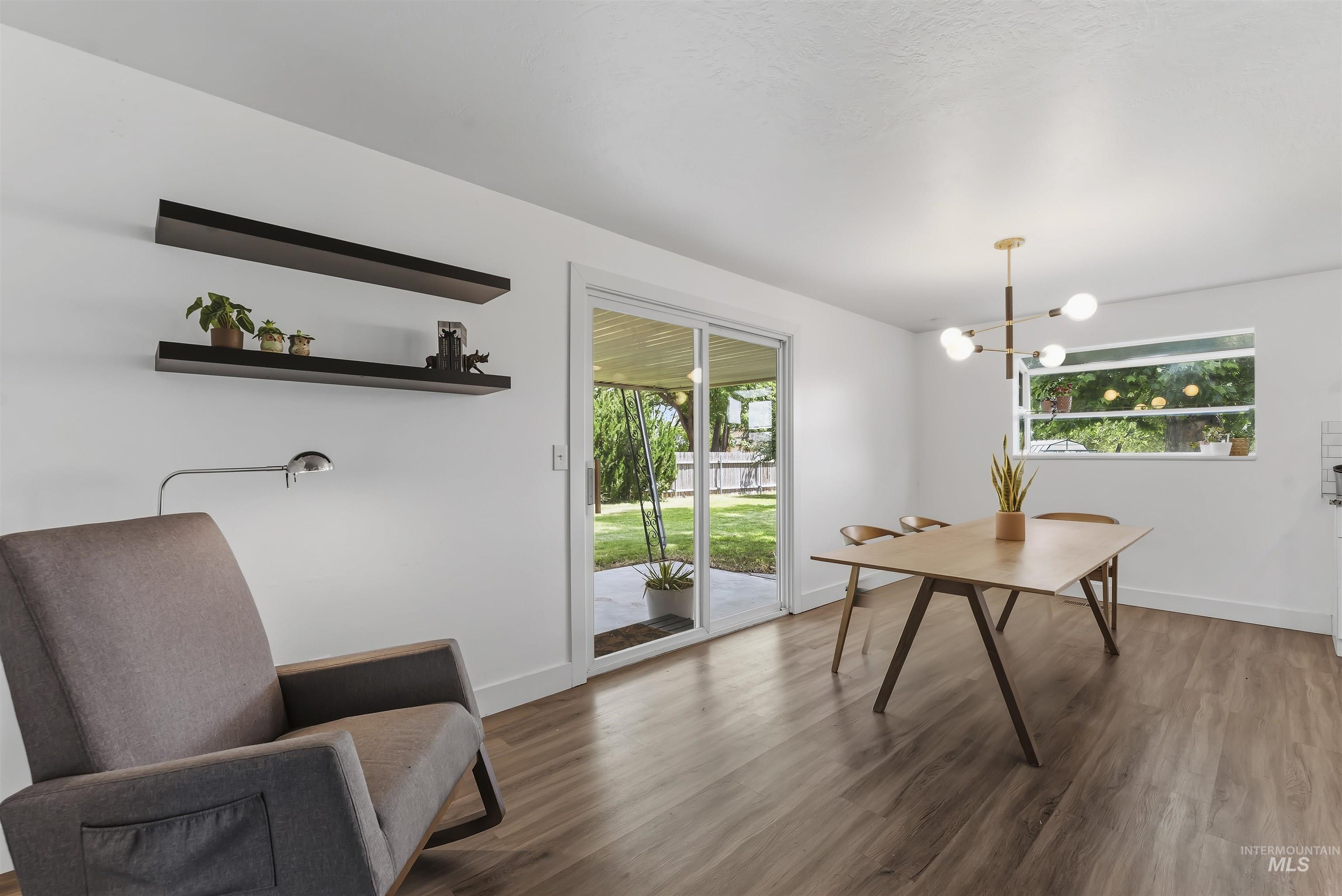 355 East Beacon Light Road Eagle, ID 83616 - Photo 11 of 47 Open concept living space featuring wood-finish flooring, a contemporary chandelier, and white baseboards