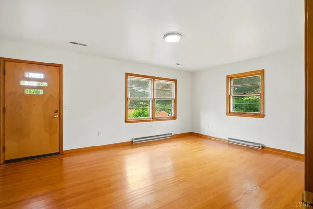 an empty room with wooden floor and windows