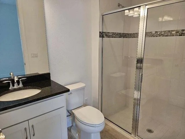 a bathroom with a granite countertop sink toilet and shower