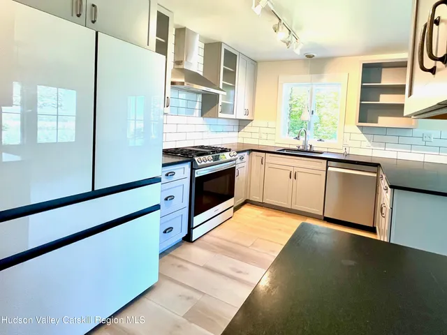 a kitchen with stainless steel appliances granite countertop a stove a sink and a refrigerator
