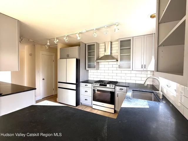 a kitchen with granite countertop a refrigerator and a stove top oven