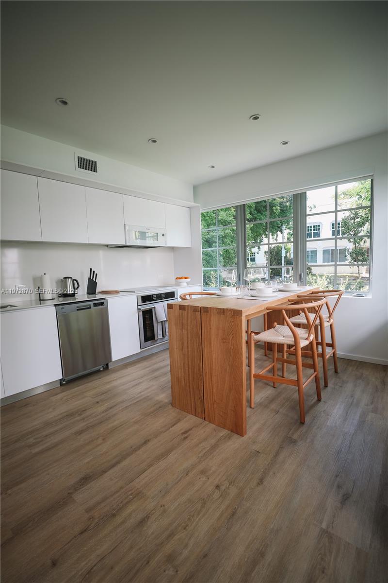 128 Northeast 46th Street, Unit 3 Miami, FL 33137 - Photo 1 of 17 a kitchen with stainless steel appliances wooden floors and wooden cabinets