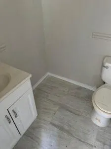 a white toilet sitting next to a white sink and vanity