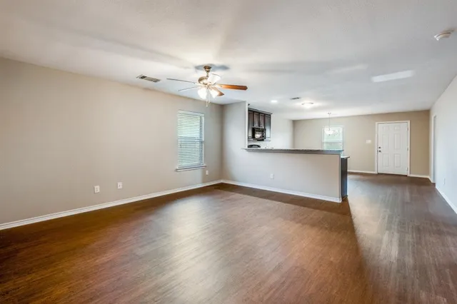 a view of a kitchen with a dishwasher a kitchen island hardwood floor and a ceiling fan