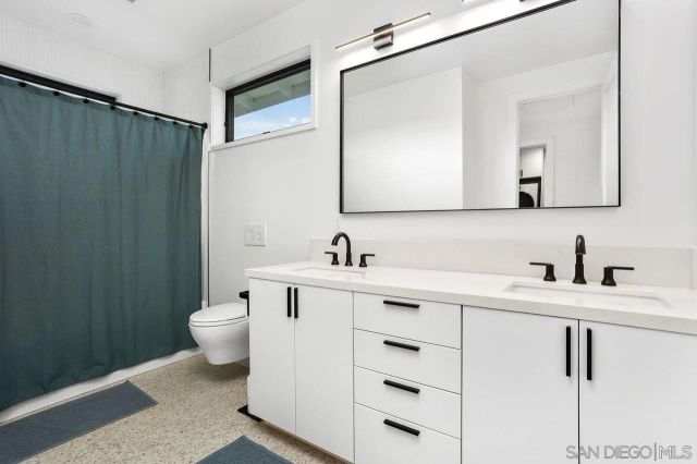 a bathroom with a toilet sink a mirror and vanity