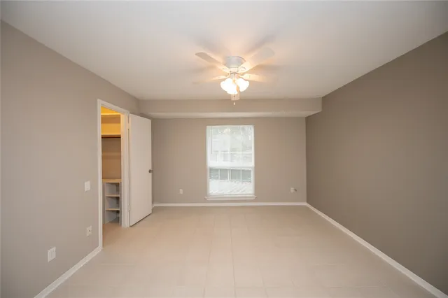 an empty room with a bathroom and a ceiling fan